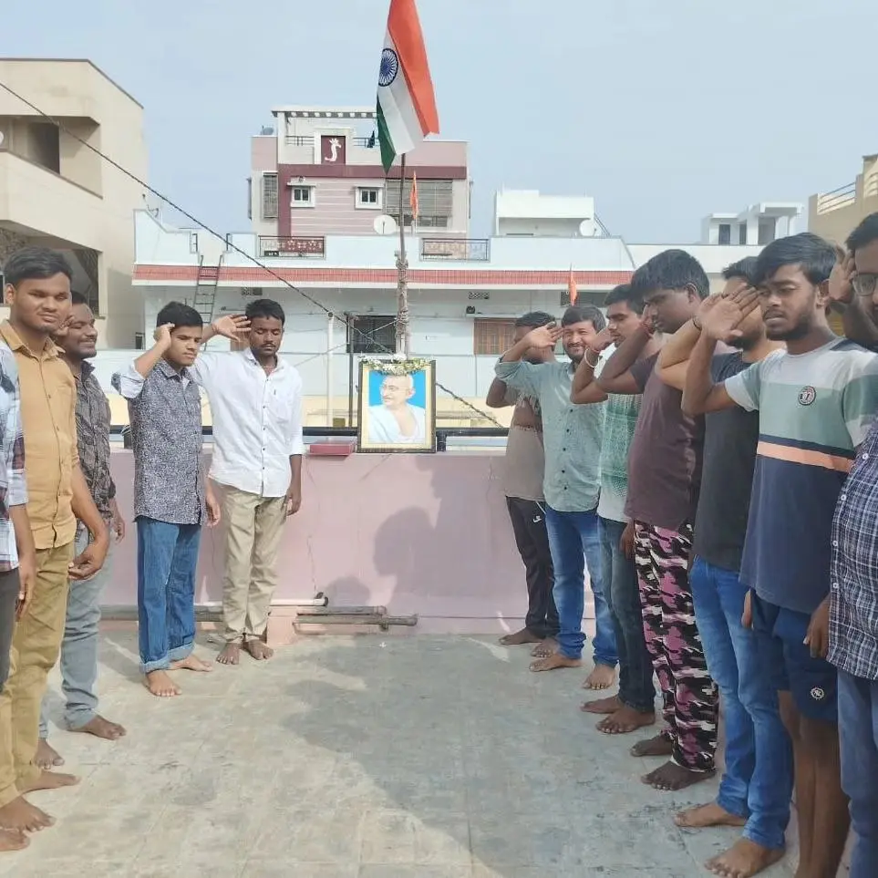 Residents saluting the flag beside a portrait of Mahatma Gandhi