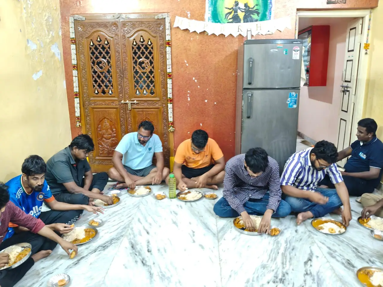 Children and visitors sharing a meal together on the floor at the home